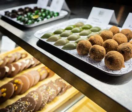 Home 31 a display of truffles and chocolate bonbons in the good chocolatier cacao bar display at greens organic market